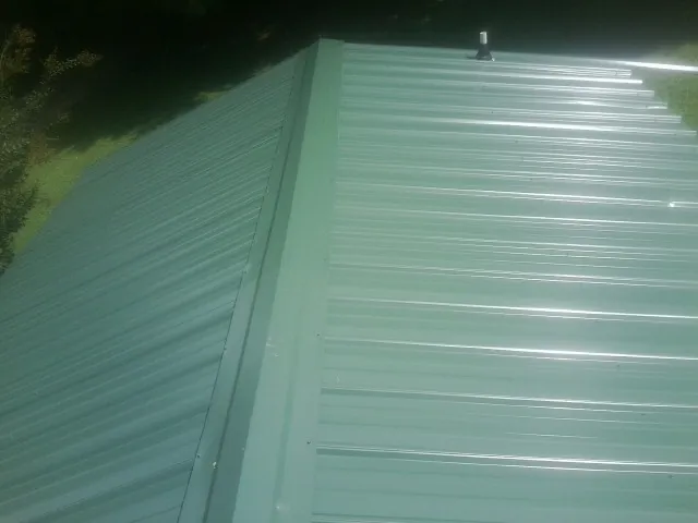 New green metal panels meeting at the ridge of a roof — Flat Roof Repair work by our crew in Chattanooga