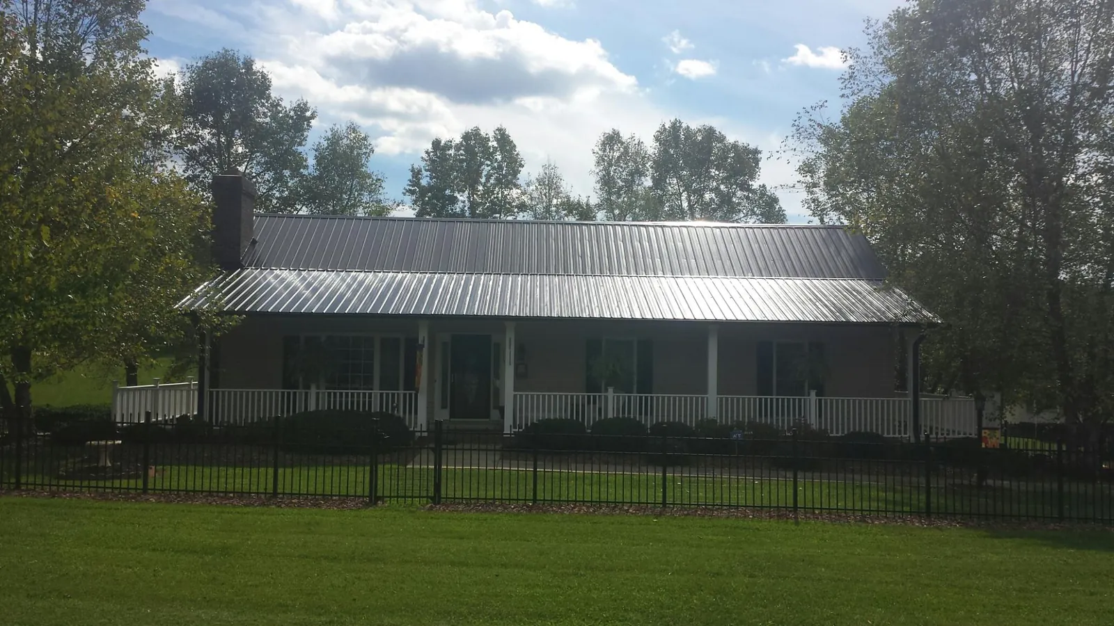 Gray metal roof on a brick ranch with a full width front porch — Gutter Guard Installation work by our crew in Chattanooga